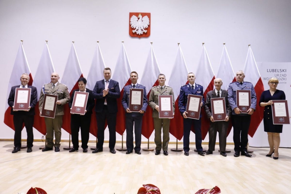 Zdjęcie grupowe nagrodzonych osób. W środku Wojewoda lubelski Przemysław Czarnek bije brawo wyróżnionym.