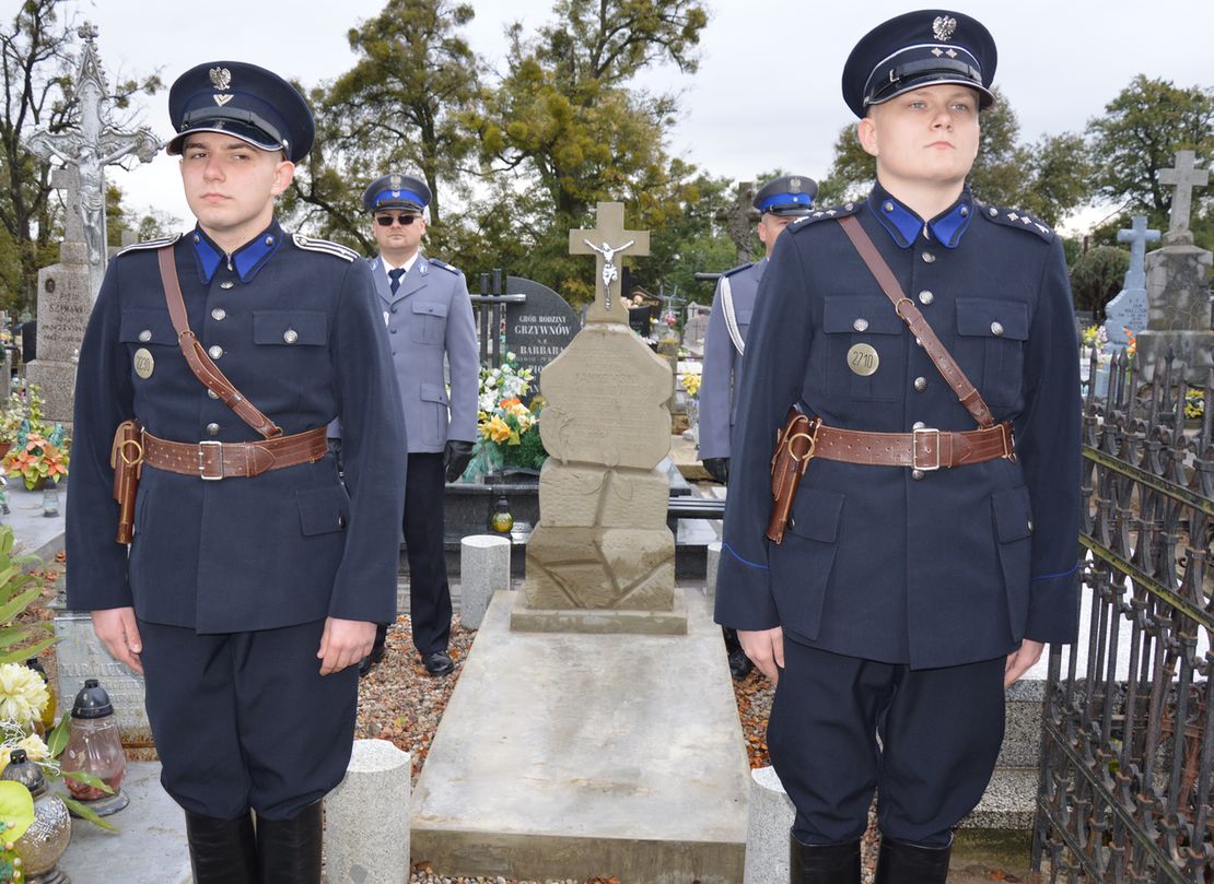 Policjanci w przedwojennych mundurach na cmentarzu stoją obok pomnika.