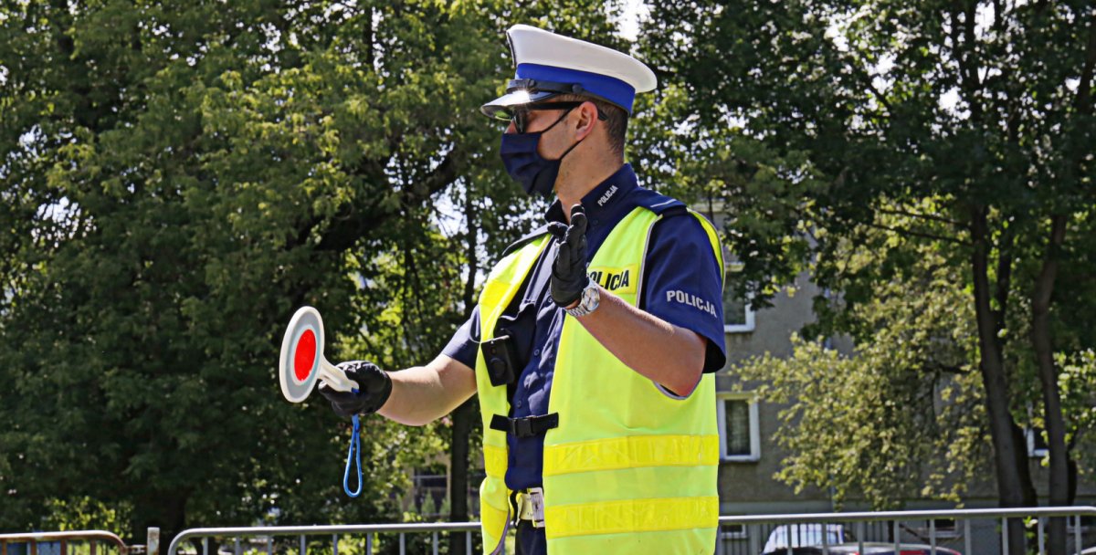 policjant z tarczą do zatrzymywania pojazdów