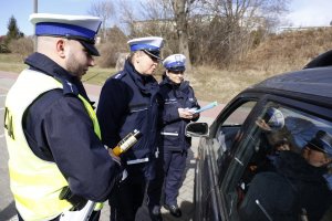 Policjant i dwie policjantki rozmawiają z kierowcą.