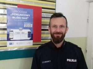 st. sierż. Dariusz Chodacki wieszający plakat programu „Dzielnicowy bliżej nas” w Szkole Podstawowej w Pniówku
