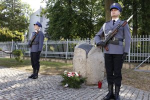 Dwóch policjantów stoi na baczność przy pomniku znajdującym się przed Komendą Wojewódzką Policji w Lublinie.