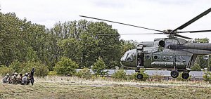 Grupa policjantów i żołnierzy czeka na podejście śmigłowca Mi 8 T.