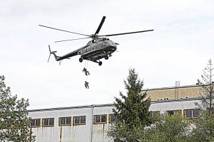Funkcjonariusze zjeżdżają na linie na dach budynku. Nad nimi wisi w powietrzu śmigłowiec Mi 8 T.