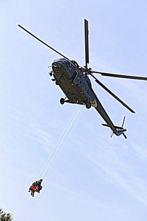 Śmigłowiec Mi 8 T w locie pod nim na linie wiszą funkcjonariusze.