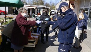 Policjanci rozdają maseczki osobom starszym na jednym z Lubelskich targów.