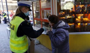 Policjantka Wydziału Ruchu Drogowego rozdaje maseczki osobom starszym na jednym z Lubelskich targów.