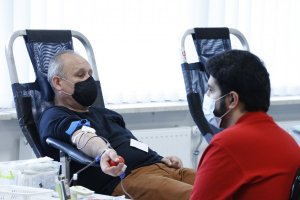 Funkcjonariusz po cywilnemu siedzi na fotelu i oddaje krew obok niego czuwa na prawidłowym przebiegiem pracownik Regionalnego Centrum Krwiodawstwa i Krwiolecznictwa w Lublinie.