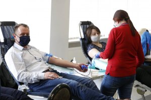 Komendant szóstego komisariatu siedzi na fotelu i oddaje krew obok pracownik Regionalnego Centrum Krwiodawstwa i Krwiolecznictwa w Lublinie pobiera krew od kobiety.