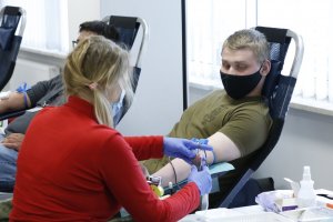 Żołnierz siedzi na fotelu przed nim pracownik Regionalnego Centrum Krwiodawstwa i Krwiolecznictwa w Lublinie pobiera od niego krew.