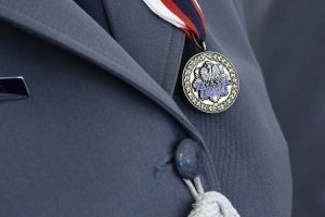 Odznaką medalu jest wieniec dębowy o średnicy 37 mm, wewnątrz którego znajduje się ośmioramienna gwiazda policyjna.  W środku znajduje się wizerunek orła ustalony dla godła Rzeczypospolitej Polskiej. Pod orłem jest umieszczona rozwinięta, granatowa wstęga z napisem: POLICJA.
