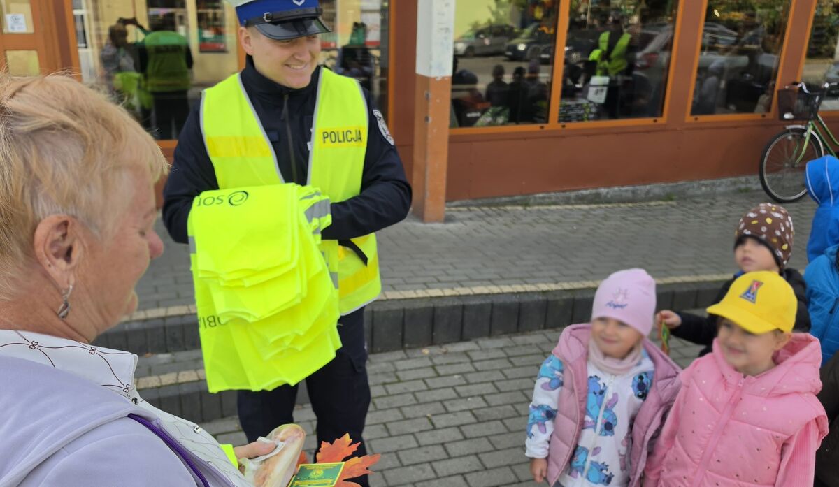 policjant z dziećmi rozdaje odblaski pieszej
