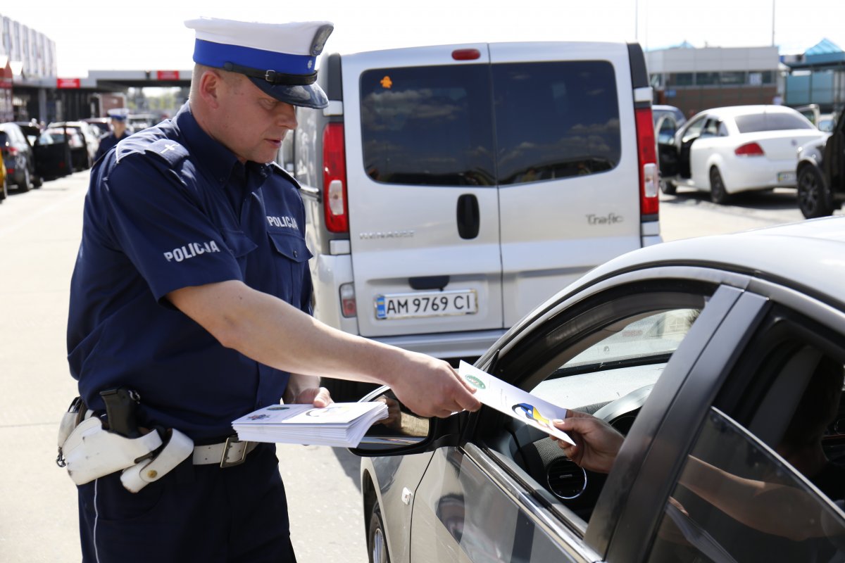 Policjant wręcza poradnik kierowcy na przejściu granicznym.