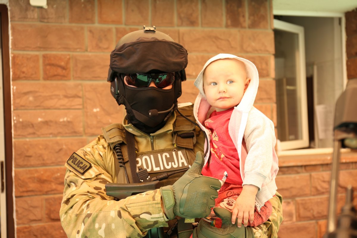 Policyjny kontrterrorysta trzyma na ręku dziecko