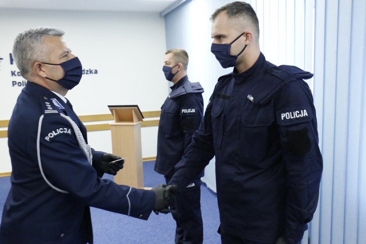 Komendant Wojewódzki Policji insp. Artur Bielecki wręcza legitymację nowo przyjętemu policjantowi.