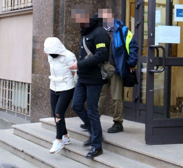 policjanci prowadzą zatrzymaną kobietę po schodach