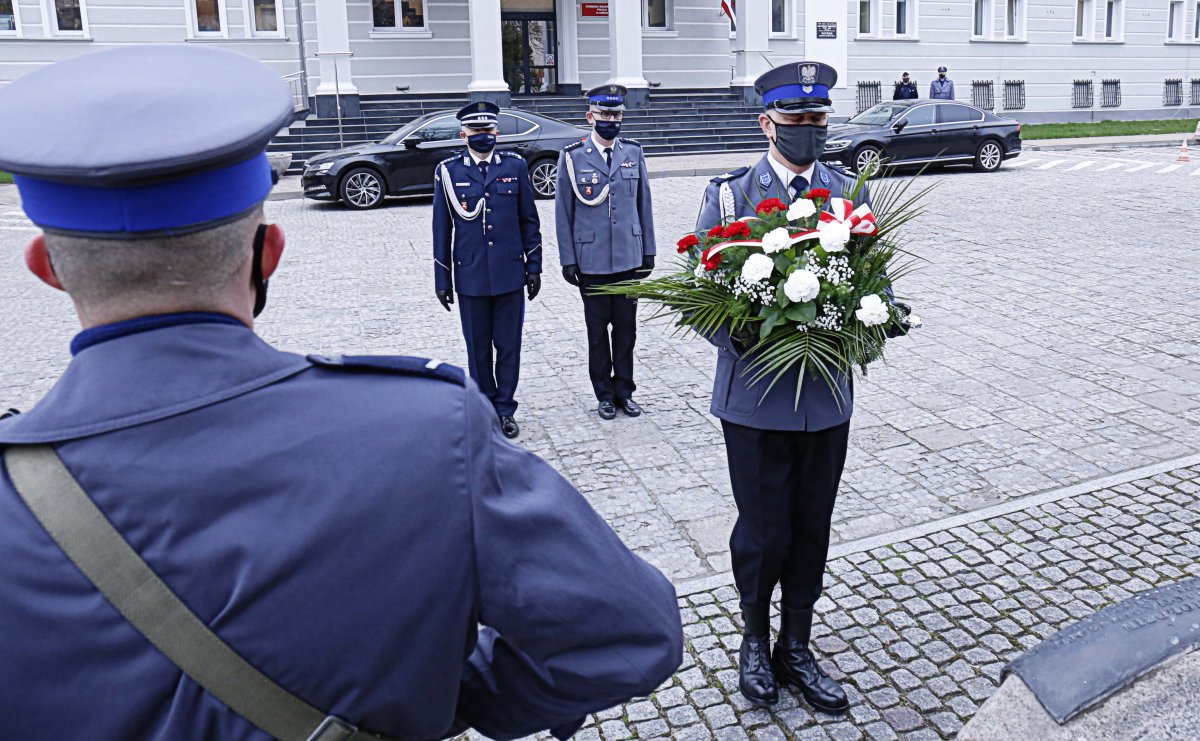 Komendant Wojewódzki Policji wraz z Wiceprzewodniczącym Dariuszem Michajłowem składa wieniec pod pomnikiem. Za nimi widać Komendę Wojewódzką Policji w Lublinie.