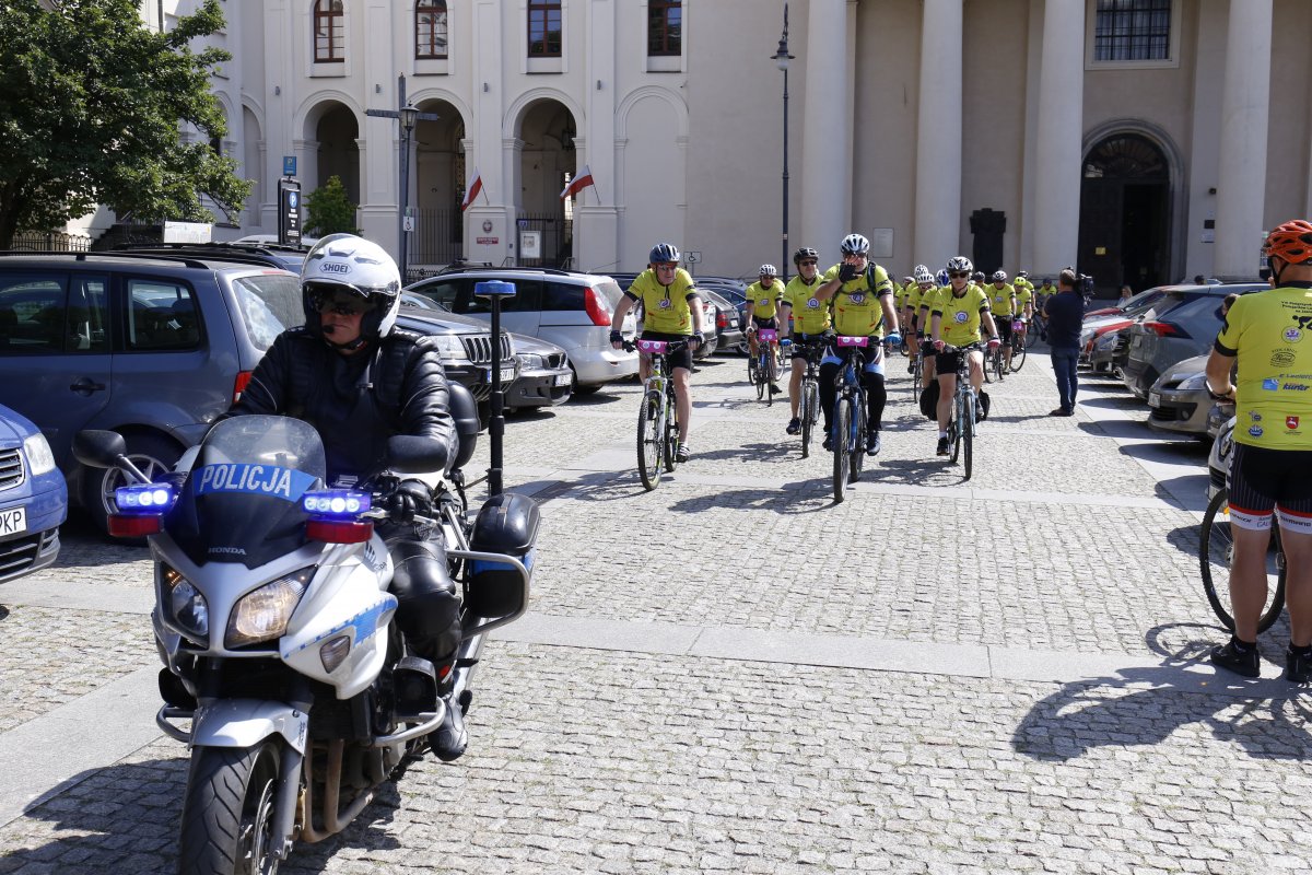 Policjant na motocyklu prowadzi pielgrzymkę.