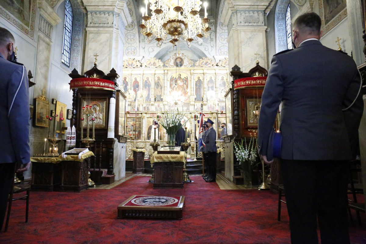 W pierwszym planie po lewej i prawej stronie zdjęcia policjanci umundurowani w mundur galowy. W drugim planie zdjęcia ołtarz kościoła.