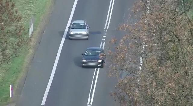 Kierowca czarnej osobówki wyprzedza inny pojazd na podwójnej ciągłej linii.