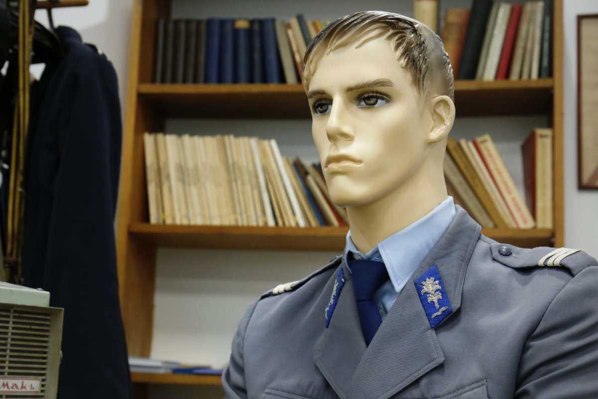 Zdjęcie przedstawia manekina ubranego w mundur milicji obywatelskiej. W drugim planie zdjęcia regał biblioteczny ze zbiorami książek.