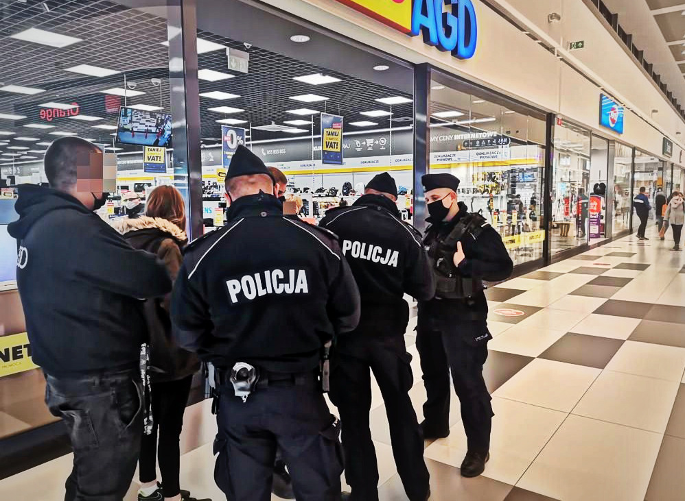 Policjanci kontrolują osoby bez maseczek zakrywających usta i nos w galerii handlowej.