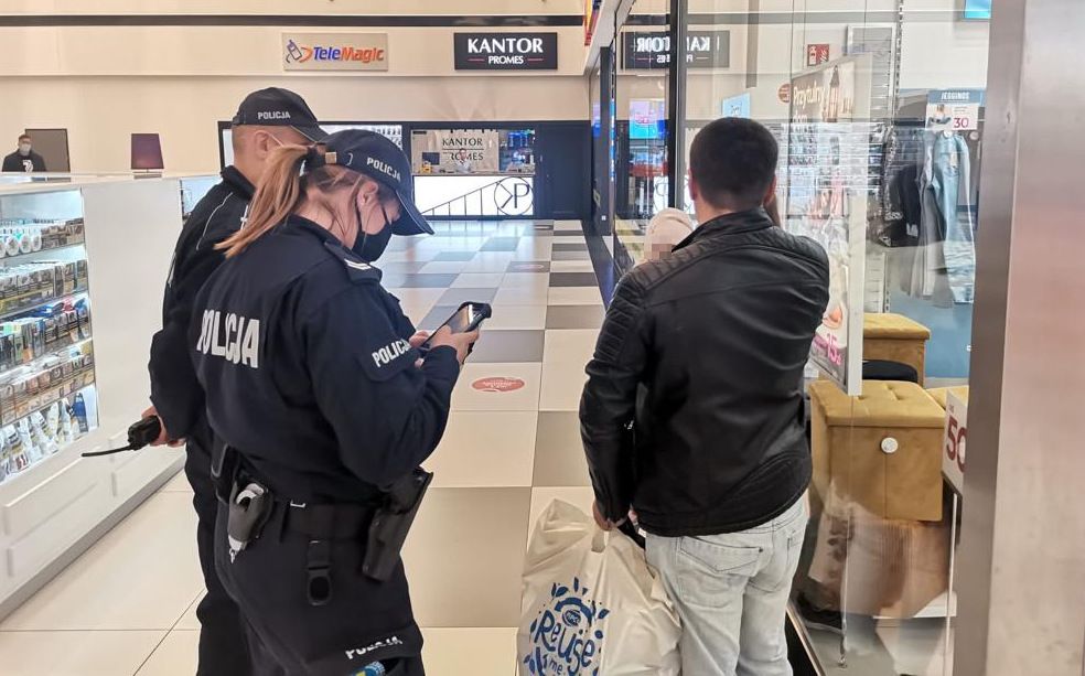 Policjanci w galerii handlowej legitymują osobę bez maseczki zakrywającą ust i nos.