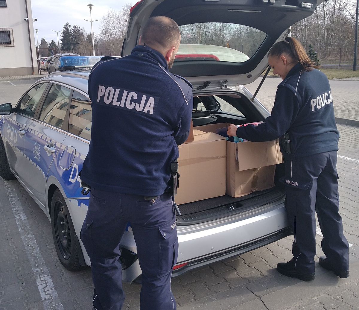policjant i policjantka układający paczki z darami do radiowozu