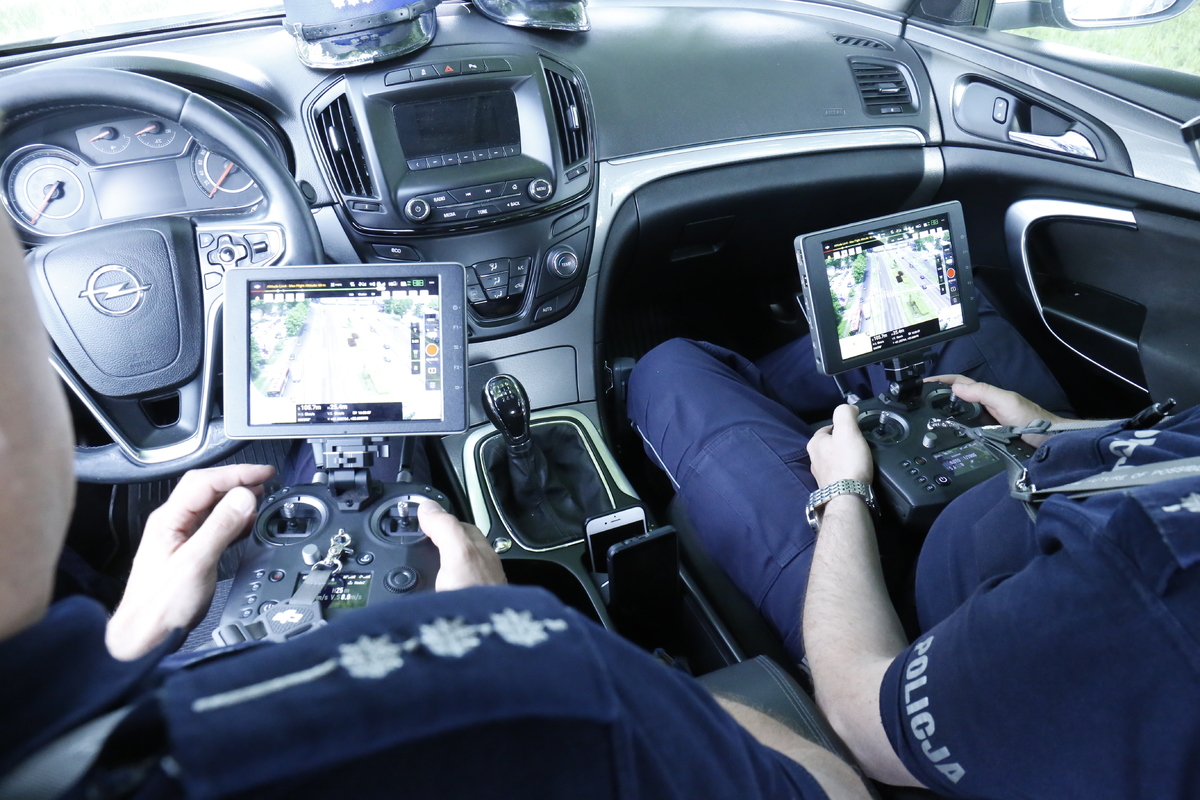 Policjanci w radiowozie sterują dronem.