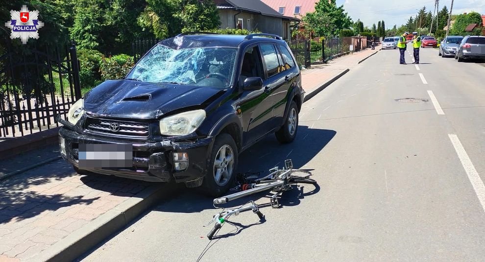 Rozbity samochód na chodniku z widocznymi uszkodzeniami po potrąceniu rowerzystki.
