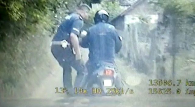 Policjant zatrzymujepieszo motorowerzystę.