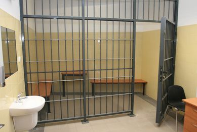 Pomieszczenie dla osób zatrzymanych wyposażone w stół i ławę.