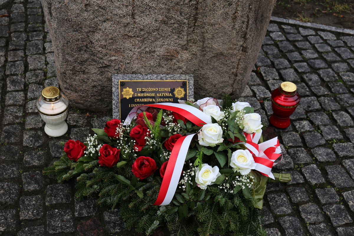 pomnik, przed nim lężą kwiaty i palą się znicze