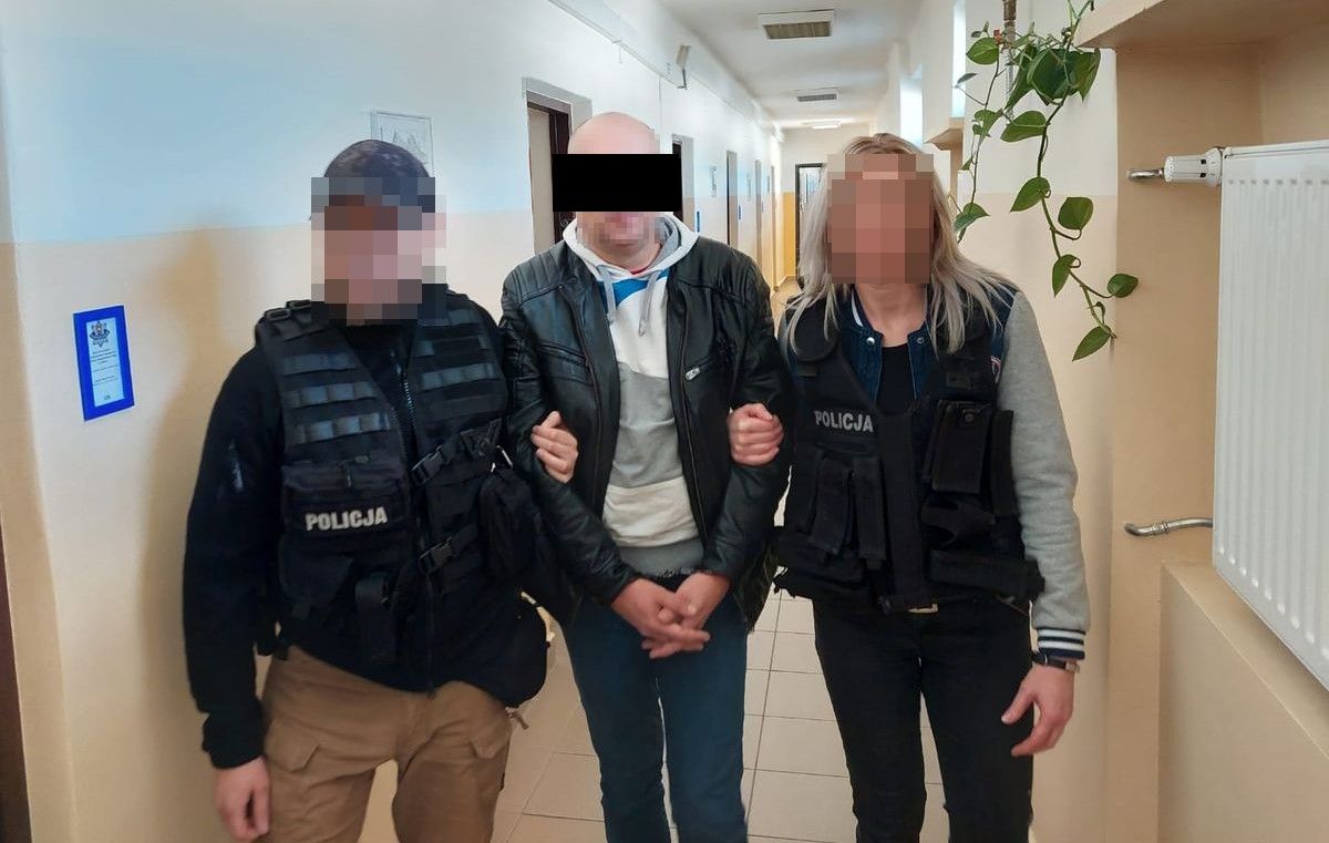 policjanci za korytarzu z zatrzymanym mężczyzną