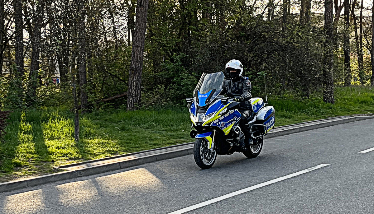 Policjant w kasku jedzie na motocyklu.