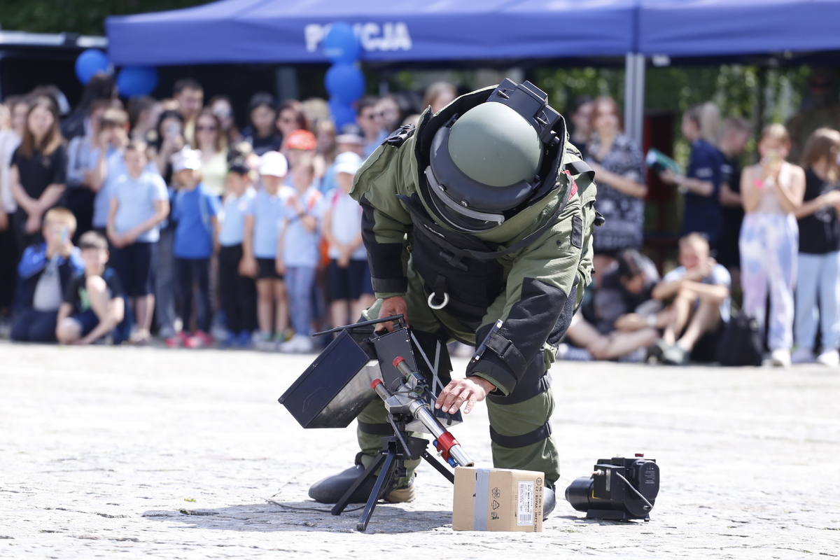 Policjant ubrany w strój ochrony przygotowuje się do neutralizacji paczki.