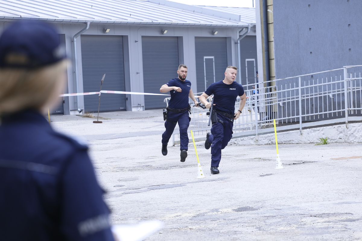 Dwóch policjantów biegnie na czas przez tor przeszkód.