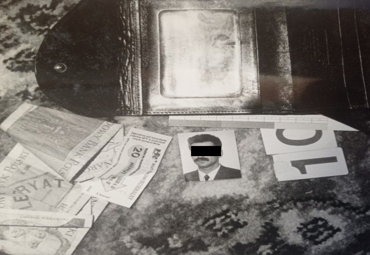 Zdjęcie koloru czarno białego na którym widać pozostawiony na miejscu zbrodni protfel wraz z fotografią sprawcy zabójstwa.