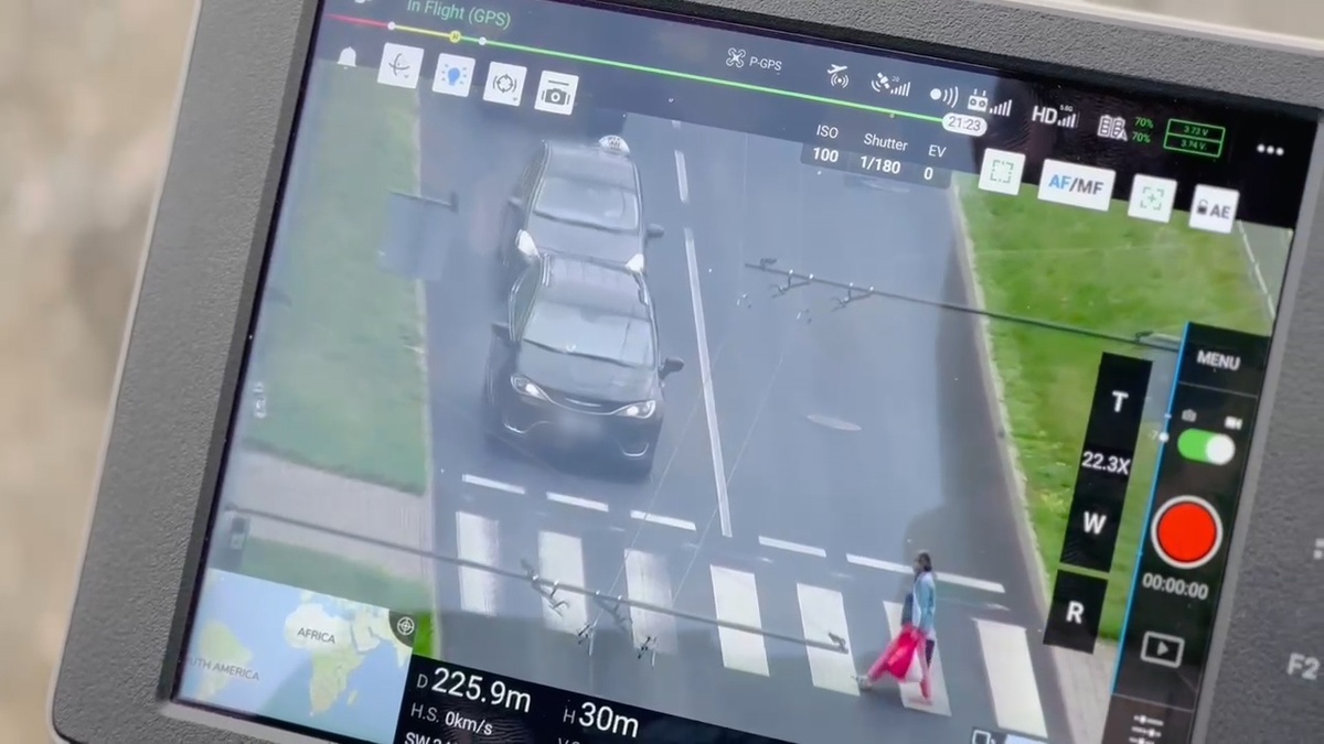 Ujęcie z kamery drona na przejście dla pieszych , gdzie osobowe auta ustępują pieszej.