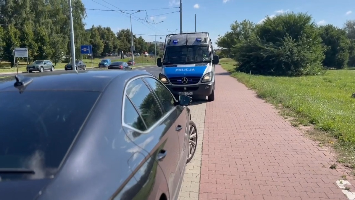 Na zdjęciu widzimy osobowe auto oraz oznakowany radiowóz.