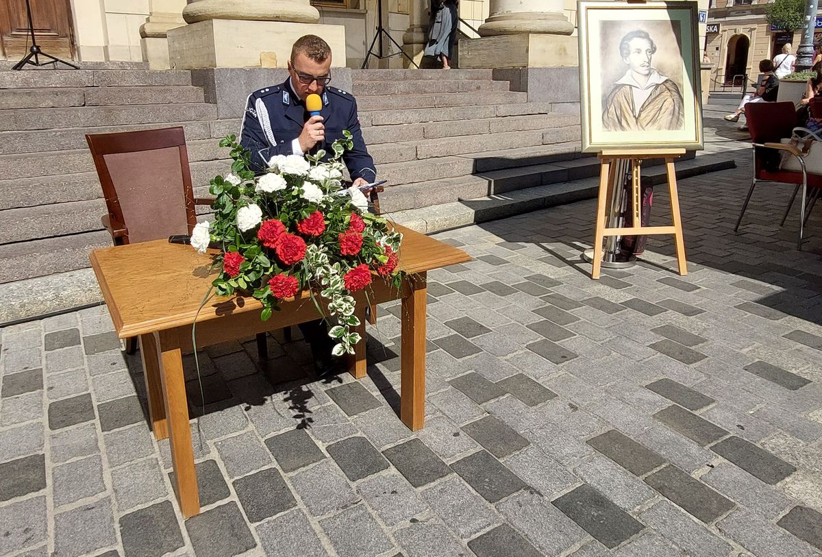 policjant czytający fragment utworu przed Ratuszem