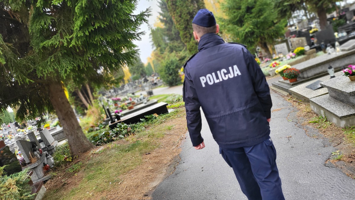 Policjant na służbie patroluje okolice cmentarza.