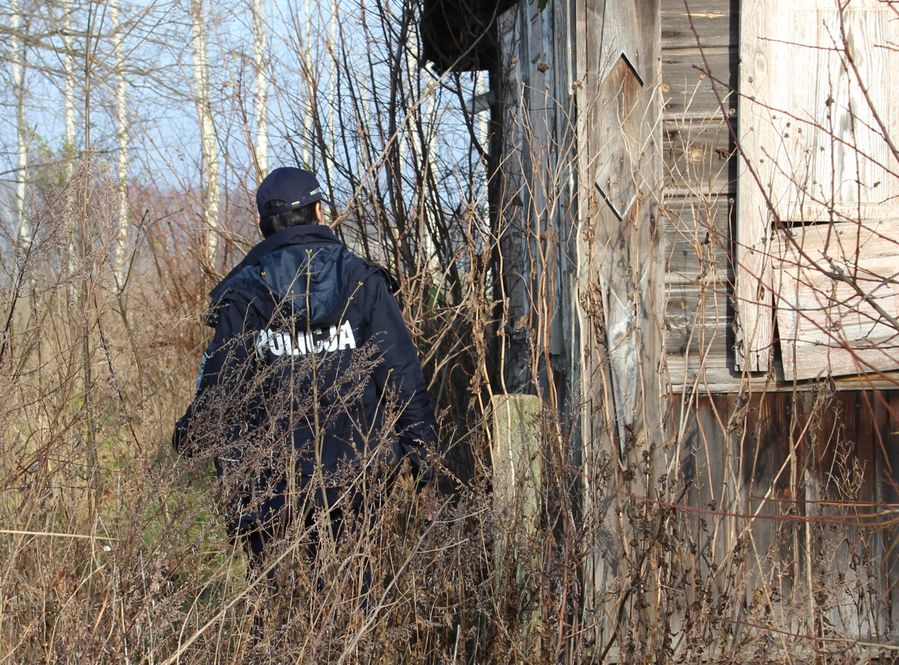 Policjant sprawdza czy w opuszczonym domu ktoś jest.