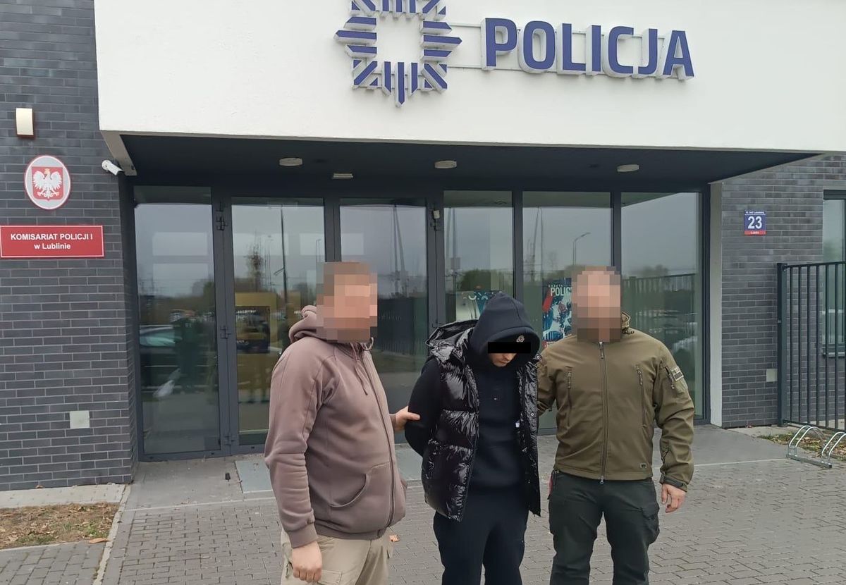 policjanci prowadzą zatrzymanego, w tle komisariat Policji