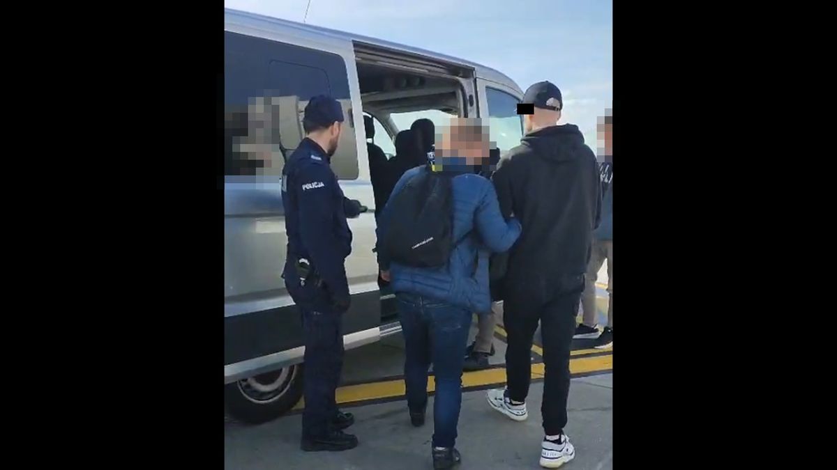 policjanci prowadzą zatrzymanego mężczyznę do radiowozu