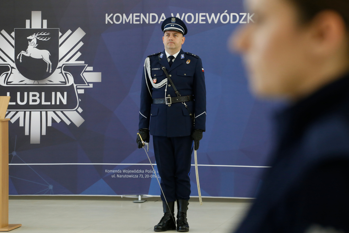 Dowódca uroczystości z szablą w ręku ubrany w mundur galowy .