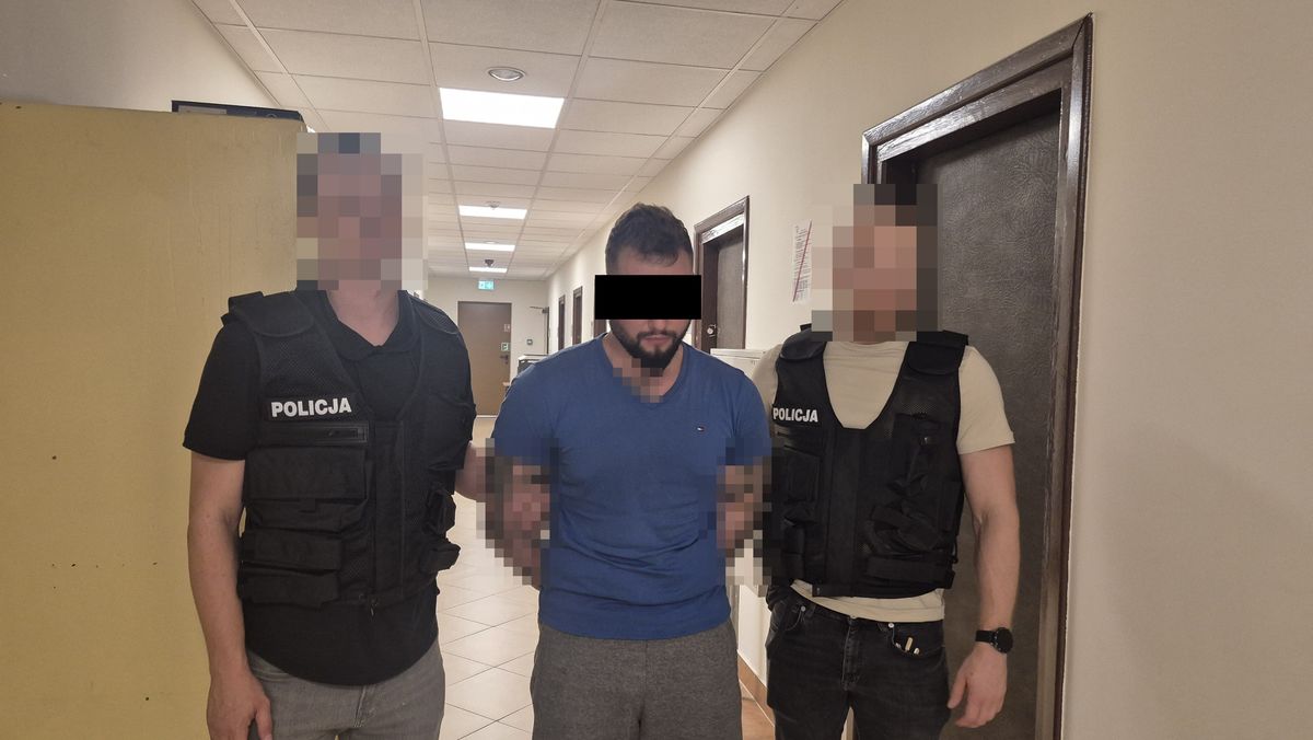 Policjanci prowadzą zatrzymanego mężczyznę.