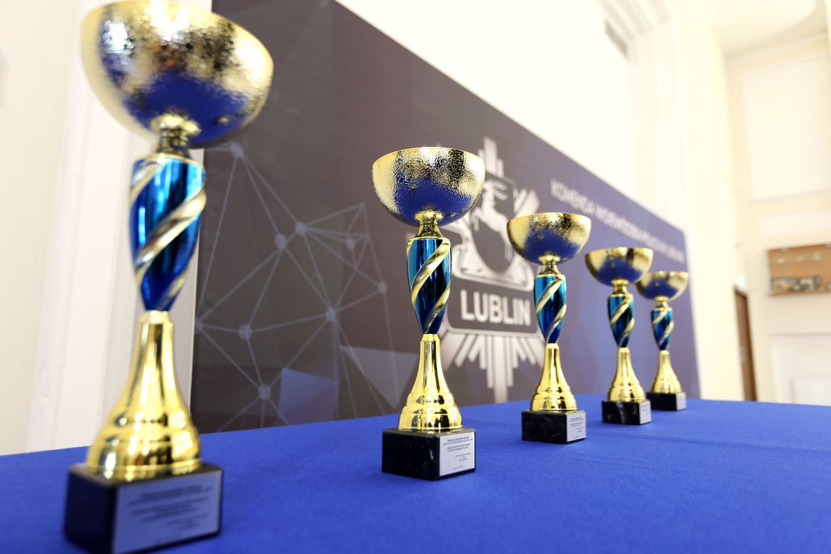 cztery złote puchary stojące na stole z niebieskim suknem 