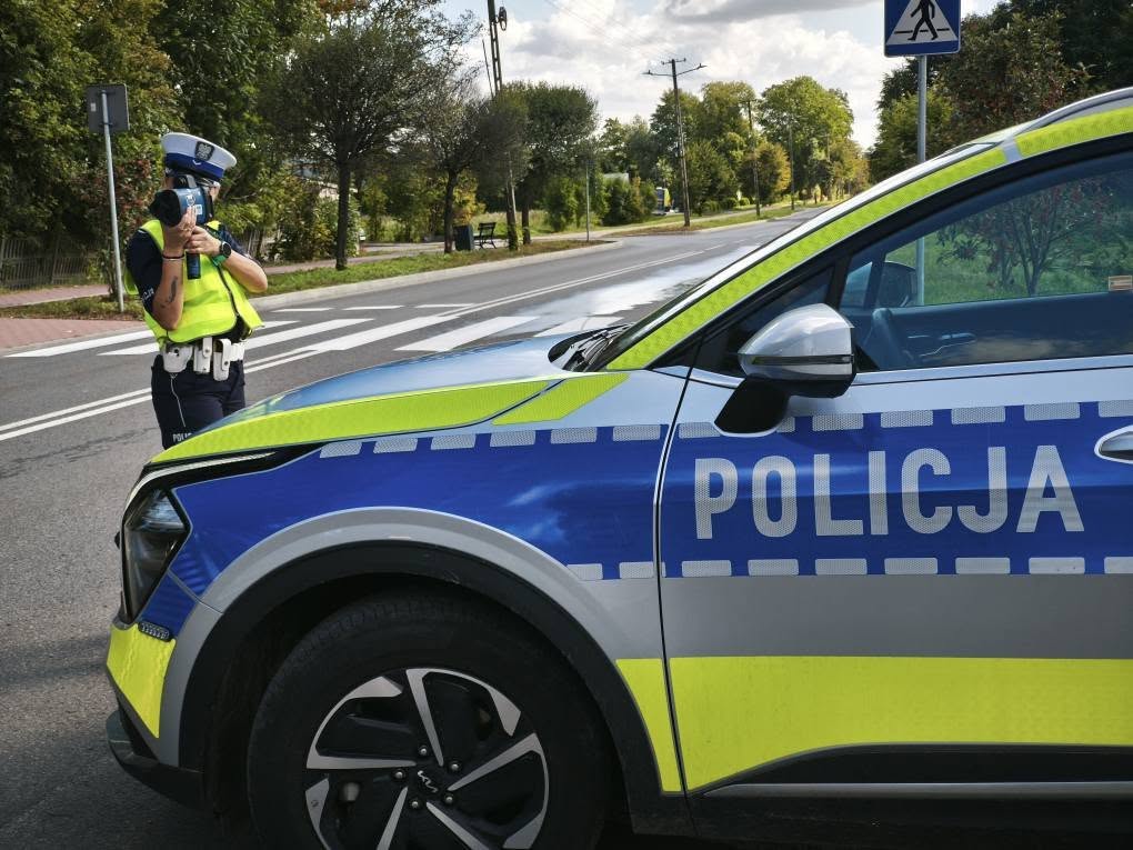 policjantka z miernikiem prędkości przy drodze obok radiowozu