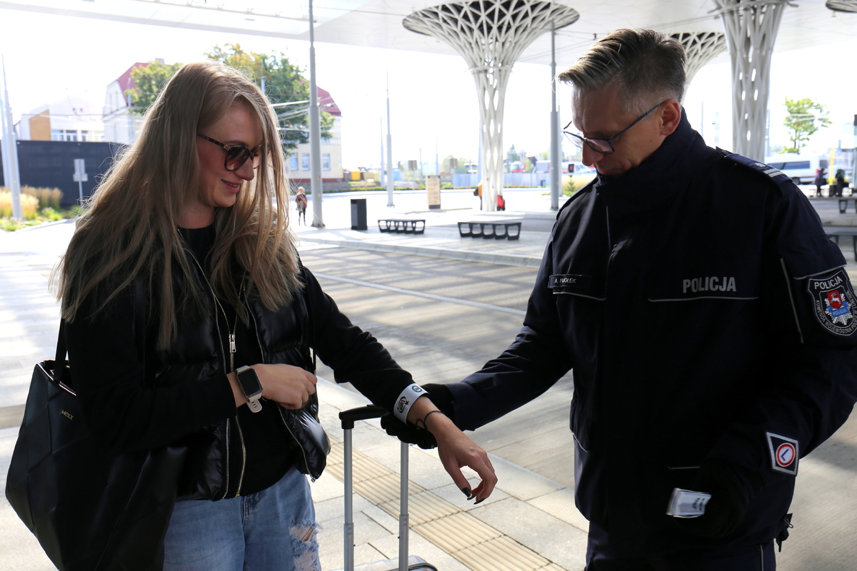 policjant rozdaje odblaski na dworcu pieszym